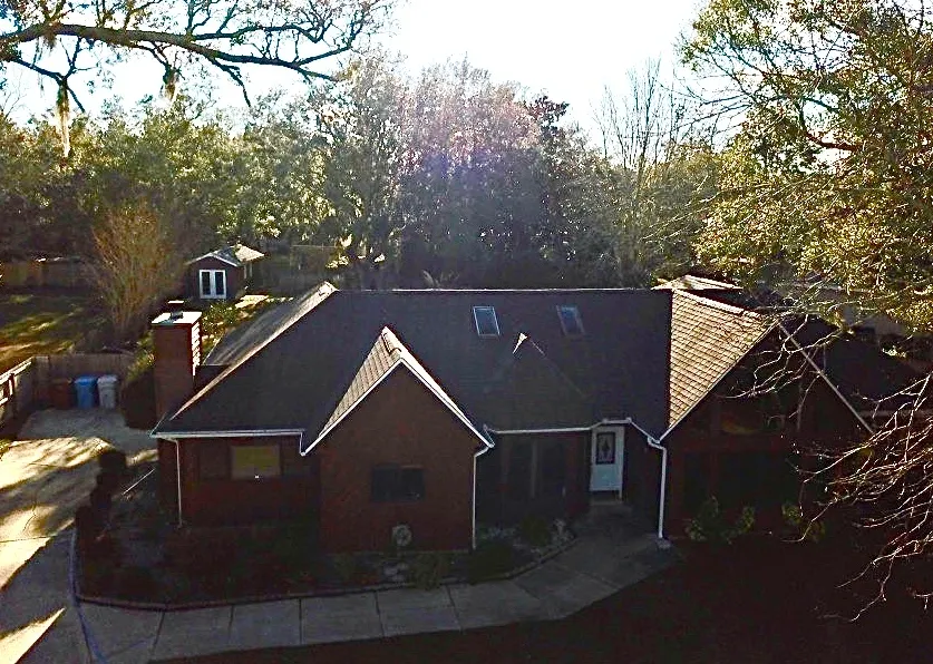 Aerial view of brown dimensional shingle hip roof with skylights on brick home in Navarre FL by H&R Roofing and Construction