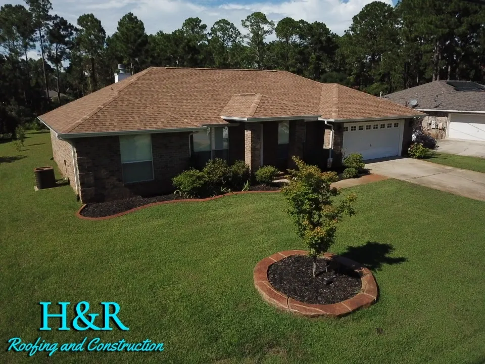 Ground-level front view of brick ranch home with completed brown architectural asphalt shingle roof in Navarre FL by H&R Roofing and Construction