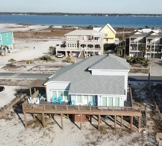 Aerial view of beachfront stilt home with gray shingle roof on Navarre Beach FL by H&R Roofing and Construction